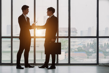 Fototapeta na wymiar Negotiating business,Image of businesswomen Handshaking. young asuan businessmen shaking hands together while standing by windows in an office