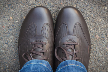 Comfortable brown leather shoes for men on asphalt road or footpath. Male footwear