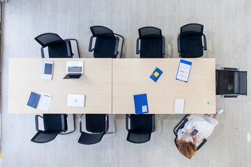 Top view of a conference room. A white rectangular table and eight black leather chairs around