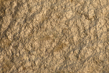 Natural background. Fragment of a granite rock in the rays of the sunset close-up.