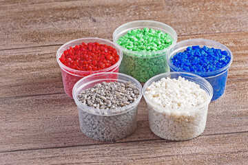 Five plastic jars with decorative stones for flower care on a wooden countertop