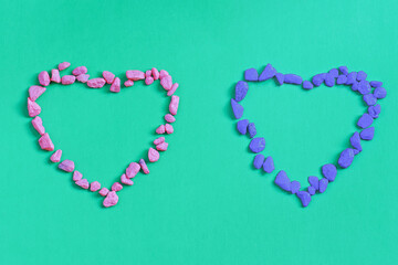 Two hearts made of decorative stones on a green background