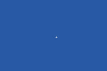 A distant passenger jet plane up high in the blue sky