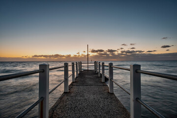 Fototapeta na wymiar Looking out over a pier against the ocean, a dusk horizon sky