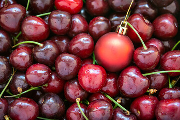 A red christmas bauble amongst ripe red cherries, horizontal