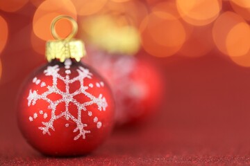 Christmas and New Years  background.Red balls with a snowflake on a  red glitter background with  yellow bokeh. Christmas beautiful festive background. Holidays Beautiful wallpaper.