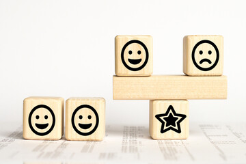 Close up custome choose smiley face and blurred sad face icon on wood cube, Service rating, satisfaction concept.