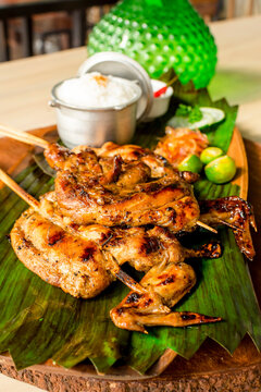 Chicken Inasal, a variant of lechon manok, on a banana leaf on top of wooden platter. It is popular grilled dish from the Western Visayas region of the Philippines