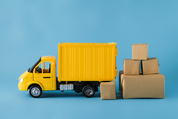 Yellow truck delivery gift box on blue background. Cargo transportation, delivery service. Transport company. Infrastructure and logistics. Unloading cardboard box. 