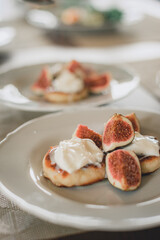 Traditional cottage cheese pancakes, cheesecake on a plate sour cream and nuts sauce, pieces of figs.