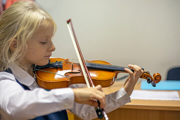  little violinist with closed eyes plays the violin, music lesson, meodika suzuki