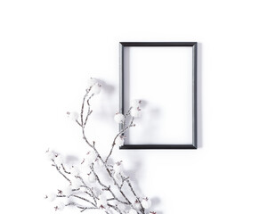 Modern winter mockup made from blank black photo frame and snowy branch. Minimalistic template for christmas, new year, invitation, banner. New Year, invitation, banner. Flat lay, top view.