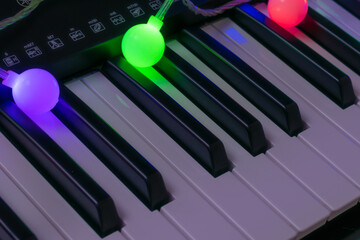 Piano keyboard. Musical background. Piano with colorful garland.