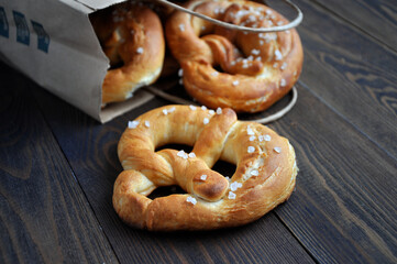 Homemade pretzels in a paper bag on a dark wooden table