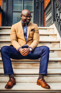 Portrait of confident African American businessman in glasses and tan blazer.