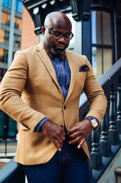 Portrait of confident African American businessman in glasses and tan blazer.