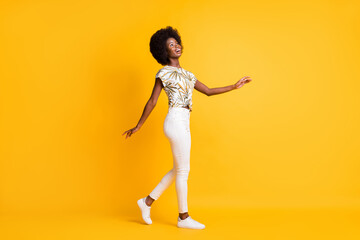 Fototapeta na wymiar Full size profile photo of optimistic cute lady walking look empty space dress t-shirt sneakers trousers isolated on yellow background