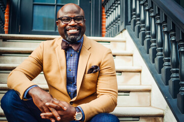 Portrait of confident African American businessman in glasses and tan blazer.