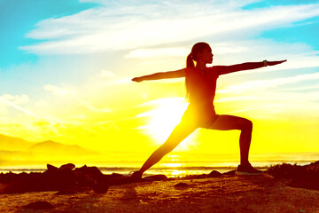 Yoga well-being woman training outdoors in morning sunrise. Wellness and health concept. Silhouette againts sun sky.