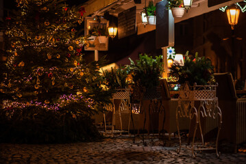 A cozy street cafe with Christmas decorations on the street of the old town in Prague. Christmas illumination. Bokeh garlands in the background. Christmas, winter, new year concept.