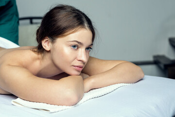Young beautiful girl in a towel with opened eyes meditates before spa treatments