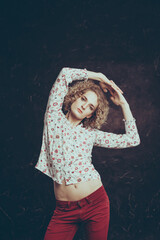 A young blond man androgyn in the image of an attractive woman in a blouse with flowers posing...