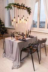 Side view of festive Christmas table setting with empty wine glasses and black plate