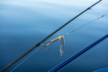 Fishing accessories baubles with a hook on a blue water background close up selective focus