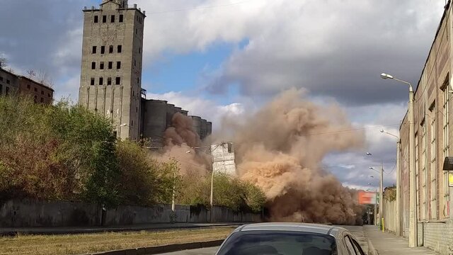 A controlled explosion of an old building. Demolition of a building on the territory of the plant. Highly dusty air after explosion.