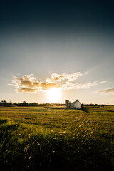 Fototapeta premium Country scene with lonely house with clouds in sunset 