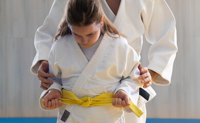 Judo trainer tying belt for his pupil before competition.