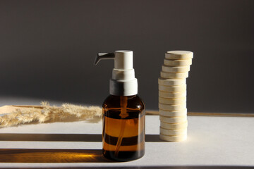 Body oil in a container with a dispenser. Solar wall. Body care, a bottle of brown liquid, pills,...