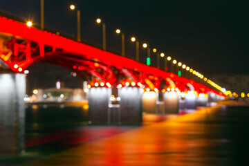 Fototapeta na wymiar background of the defocused lights of the night city, a bridge across the river