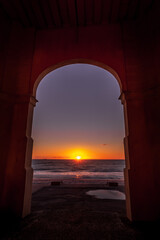 Sunset view and silhouette of the beach side from arch window 