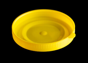 Yellow plastic jar lid isolated on black background.