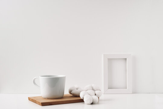 Frame, cotton and a cup on a wooden board, white background. Mock up, copy space. Folk. © Natalya Lys