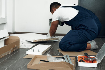 Furniture assembly process. Worker in overalls and white footwear. The choice of fittings for furniture. Do it yourself.