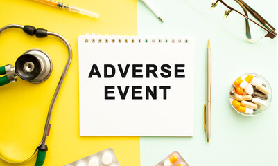 Text ADVERSE EVENT on notebook with stethoscope and pen on yellow background.
