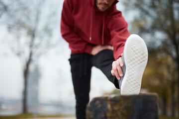 Athletic sporty man training in hoodie sweatshirt in urban city park.