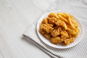 Homemade Fried Chicken Bites and French Fries on a plate, side view. Copy space.