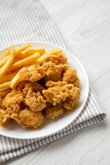 Homemade Fried Chicken Bites and French Fries on a plate, side view. Copy space.