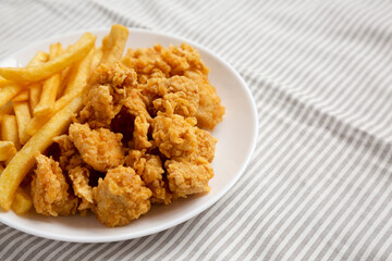 Homemade Fried Chicken Bites and French Fries on a plate, side view. Copy space.