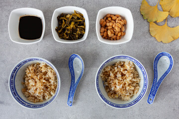 Natto-Mahlzeit in dekorativen Schalen. Zutaten: Reis, Sojasauce, Natto-Sojabohnen, eingelegtes Senfgrün. Flache Ansicht.
