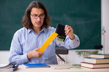 Young male teacher in front of green board