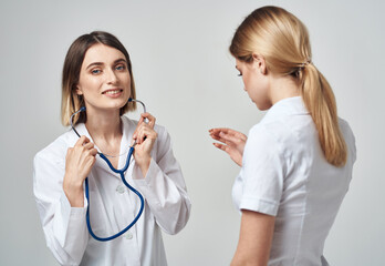 A nurse with a stethoscope and a patient on a light background