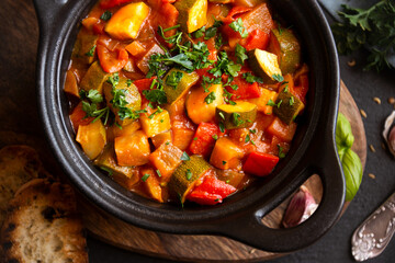 Cooked various chopped vegetables with herbs in a black cooking pot