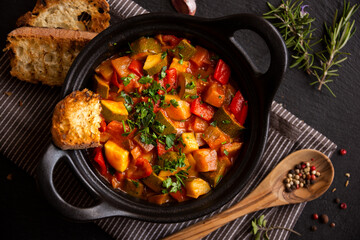 Cooked various chopped vegetables with herbs in a black cooking pot