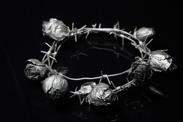 Silver crown of thorns and rose on black background