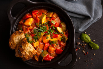 Cooked various chopped vegetables with herbs in a black cooking pot