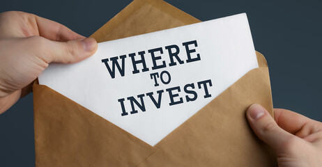 Male hands holding craft envelope with text WHERE TO INVEST on blue background